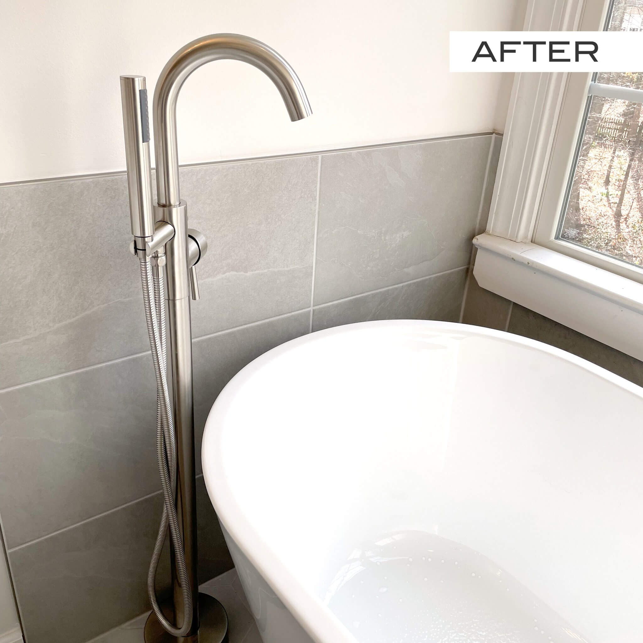Sleek modern freestanding bathtub faucet next to a white tub.