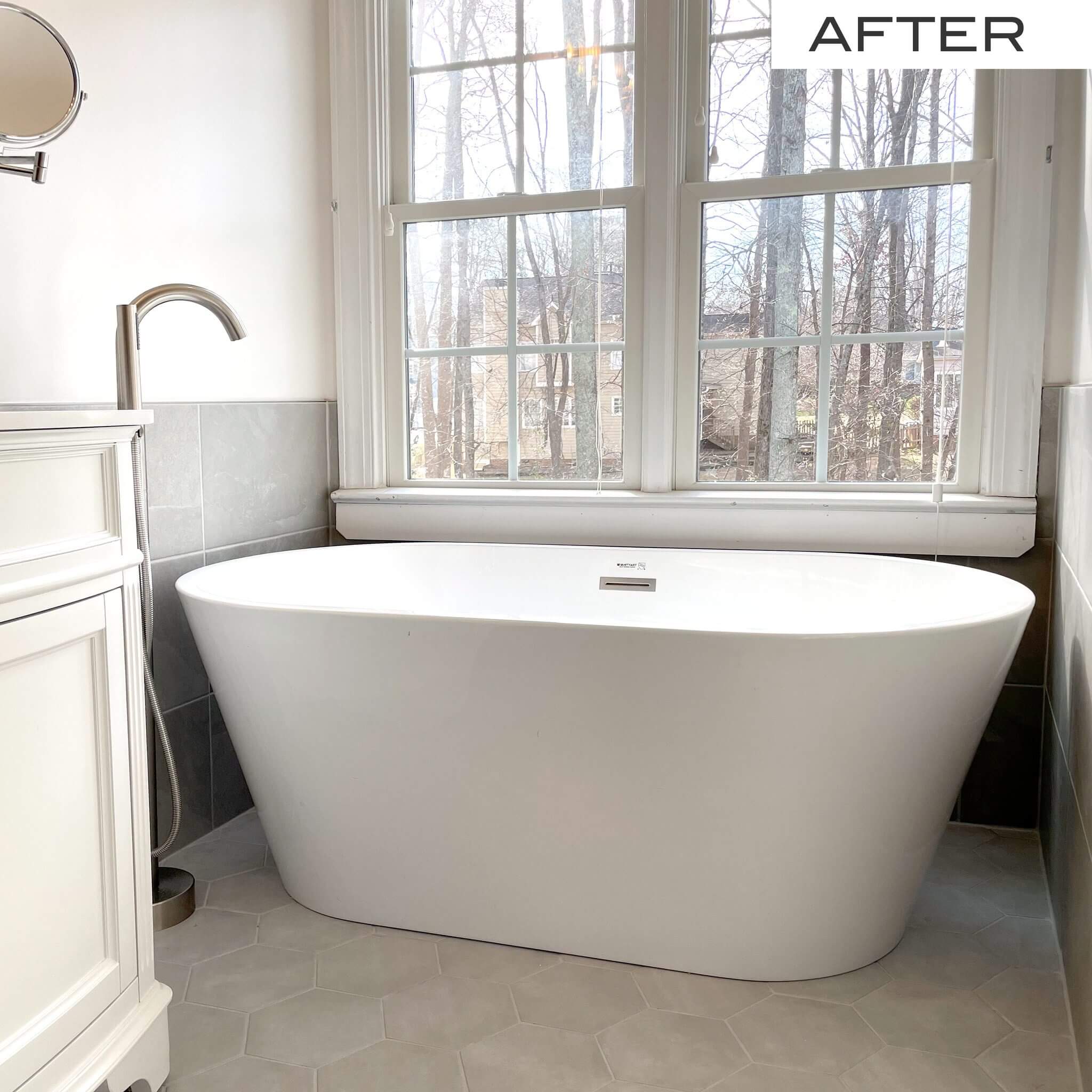 Modern white freestanding bathtub in a bright, renovated bathroom.
